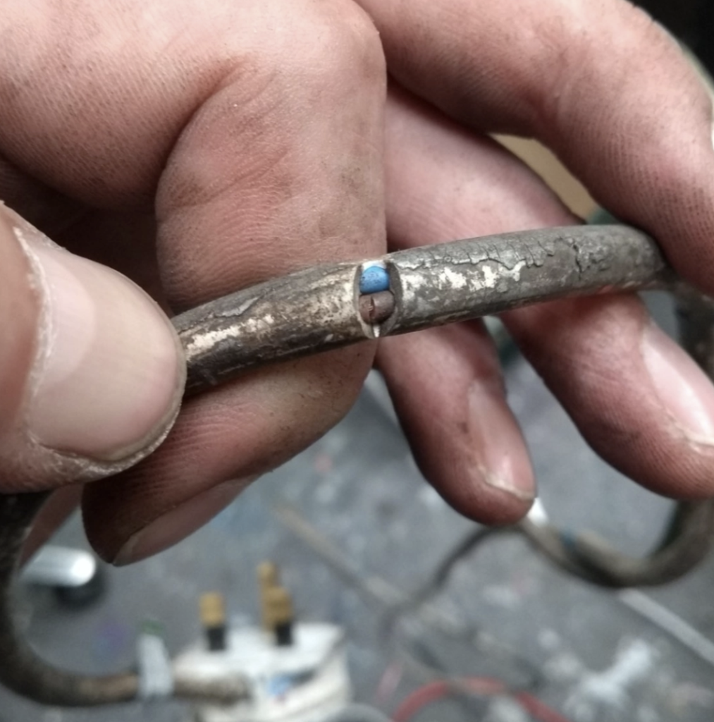 PAT tested | Person holding a cable which has split in the middle.