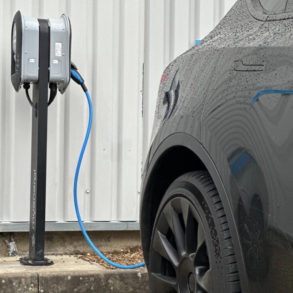 Electric car charger installation | Parked car with blue charging cable connected to charger. 